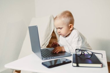 Bir dizüstü bilgisayara sabitlenmiş meraklı bir çocuk, teknolojinin erken çocukluk eğitimi üzerindeki artan etkisini ve genç çocuklar için öğrenme deneyimlerini geliştirme yollarını temsil ediyor.