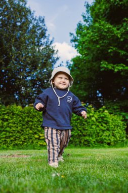 Renkli şapkalı meraklı bir çocuk neşeli, neşeli, neşeli, mutluluk ve merakla dolu bir ortamda harikalar yaratan bir parkı keşfediyor.