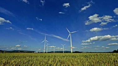 Büyük rüzgar türbinleri bulutlu mavi gökyüzüne karşı enerji üretir. Güneşli mavi gökyüzünde dönen uzun bir rüzgar türbini görüntüsü. Yenilenebilir enerji üretimi.