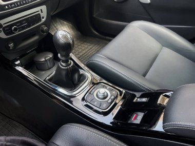 Bu görüntü, gelişmiş bir sürüş deneyimi için manuel vites değişimi, konsol kontrolleri ve lüks koltukları içeren modern siyah bir arabanın iç görüntüsünü gösteriyor.