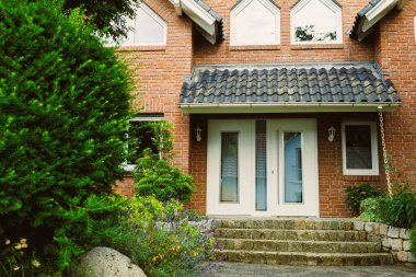 Bu güzel tasarlanmış tuğla ev, canlı bahçeler ve yemyeşil ile güçlendirilmiş davetkar bir girişe sahip. Mahalleye sıcaklık ve zarafet katıyor.