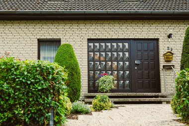 Çağdaş ev girişinde güzel bir el yapımı kapı ve canlı bir peyzaj, sıcak, davetkar atmosferi geliştirme ve cezbedici bir karşılama yer alıyor.