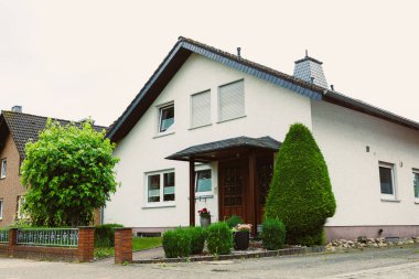 Bu modern ev, manikürlü çitlerin çerçevelediği, canlı yeşillik ve rahatlama alanları ile yaşayan sakin banliyölerin davet ettiği bir girişe sahip.