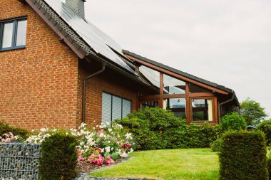 Enfes bir modern mimariye sahip çarpıcı bir tuğla ev. Çiçeklerin açtığı canlı bir bahçe ve düzgünce budanmış çitlerle süslenmiş güzel bir manzara yaratıyor.