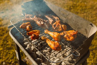 Sulu tavuk bacakları ve ızgarada cızırdayan nefis pirzolalar, aromatik dumanla çevrili, ağız sulandırıcı bir barbekü sahnesi yaratıyor açık hava toplantıları için ideal.