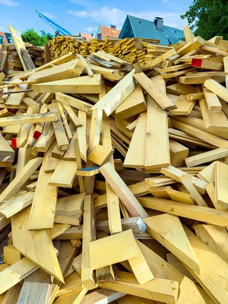 Hareketli şantiyede, çeşitli ahşap projeler için ideal boyutlarda ve şekillerde, yüksek bir ahşap kalas ve kiriş yığını bulunuyor.