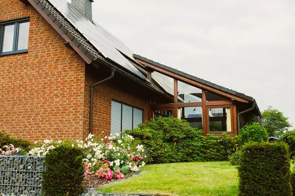 Enfes bir modern mimariye sahip çarpıcı bir tuğla ev. Çiçeklerin açtığı canlı bir bahçe ve düzgünce budanmış çitlerle süslenmiş güzel bir manzara yaratıyor.