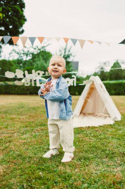 Neşeli bir çocuk renkli çiçeklerle dolu canlı bir alanda neşeli bir oyun oynuyor, neşeli kiraz kuşlarıyla parlak bir çadırda oynuyor, neşeli masumiyetin ve çocukluk sevincinin özünü yakalıyor.