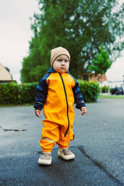 Parlak sarı bir yağmurluk ve rahat bir şapka giymiş neşeli bir çocuk neşe içinde ıslak bir çevreyi keşfediyor. Masumiyetlerini, meraklarını ve saf neşelerini sergiliyor.