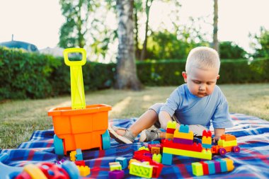 Neşeli, neşeli, neşeli bir bebek, neşe dolu, neşe dolu, neşe dolu, neşeli anlarda, yumuşak bir battaniyenin üzerine renkli bir kule inşa ederken yaratıcılığını sergiliyor.