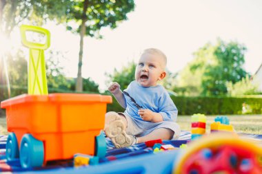 Neşeli, mutlu bir bebek renkli yapı taşlarını keşfediyor ve onlarla etkileşime geçiyor ve güneş ışığında bir parkta canlı bir oyuncak arabası, çocukluğun saf mutluluğunu ve masumiyetini gösteriyor.