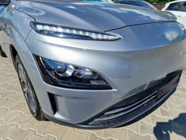 Sivri dizayn çizgileriyle ve gelişmiş görüş mesafesi için LED farlarıyla övünen bu şık gümüş renkli elektrikli arabanın parlak ön görüntüsüne yakından bakın.