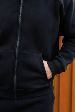 Bu yakın plan görüntüde şık bir siyah kapüşonlu, şık bir fermuarı ve ön cebi var. Sıradan geziler için ideal, modern moda ile harmanlanmış bir konfor.