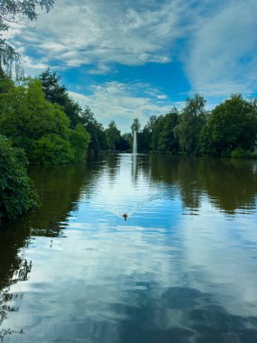 Bereketli bir göl hayal edin, yemyeşil, büyüleyici bir çeşme, ve açık mavi gökyüzünün altında yansıyan bulutlar, doğa severler ve rahatlama için mükemmel.