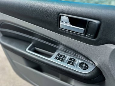 Bir arabanın kapısının yakın çekimi, şık bir sapı ve pencere kontrol düğmelerini, modern otomotiv tasarımını ve günümüz araçlarında gelişmiş işlevselliği ön plana çıkarıyor