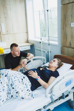 Genç bir çift bir çocuğun doğumu için hazırlanıyor. Kadın doğumhanedeki yatakta yatıyor ve erkek de onu destekliyor. Doğum sırasında kadına destek olmak..