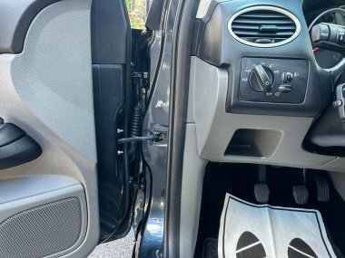 Otomotiv iç mekanlarının modern tasarımı ve işlevselliğini vurgulayan, kapı, kontrol paneli ve zemin paspaslarını gösteren bir arabanın ayrıntılı görünümü