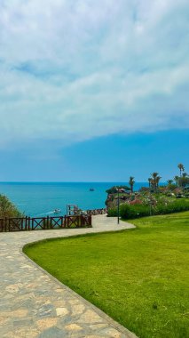 Berrak suların, canlı yeşil çimlerin ve ufukta gezinen dolambaçlı bir yolun olduğu çarpıcı bir kıyı manzarası hayal edin. Ziyarete gelen herkese derin bir rahatlık ve huzur getiriyor.