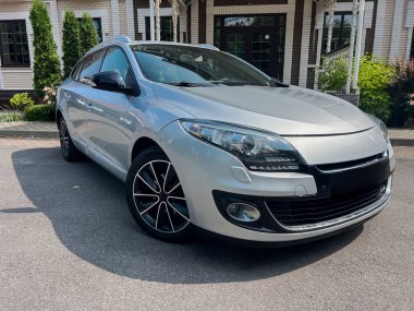 Modern tasarım elementleri ve spor alaşımlı tekerlekleri olan parlak gümüş renkli bir sedan, şehir ortamında park edilmiş. Otomotiv meraklıları ve araba galerileri için ideal.