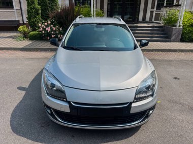 Güzel manzaralı bir arazinin önüne park etmiş parlak gümüş renkli bir araba çarpıcı tasarımı, somut modern otomotiv estetiği ve yenilikçi özellikleri sergiliyor.