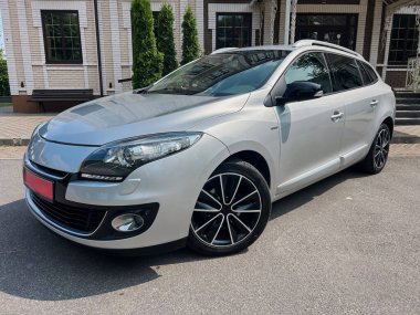 Bu çarpıcı gümüş hatchback parlak çizgilere ve şık siyah jantlara sahip, verimli yeşilliğe karşı güzelce park edilmiş, otomotiv meraklıları ve hayranlarına hitap eden