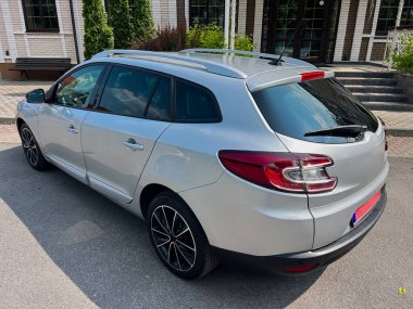 Kalabalık bir şehirde park etmiş şık, gümüş renkli bir steyşın araba modern tasarımını ön plana çıkarıyor, aile gezileri ve günlük seyahatler için ideal, konfor ve pratik olanaklar sunuyor.