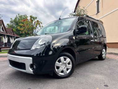 Gösterişli siyah bir minibüs, modern tasarımı ve ferah iç tasarımı, aile ve günlük taşımacılık için mükemmel olan pitoresk bir mahallede park halinde.