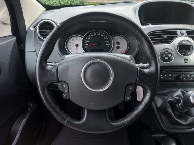 Çarpıcı bir iç çekim modern arabaların direksiyon ve gösterge panelini yakalar, günümüz otomotiv tasarımının basitliğini, sofistikesini ve zarafetini vurgular.