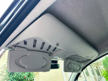 Bu yakın plan resim, modern otomotiv tasarımını somutlaştıran, şık bir güneş güneşliği ve gelişmiş bir havalandırma sistemini vurgulayan bir aracın iç çatısını sergiliyor.