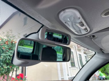 Bu görüntü, sürücülerin ve yolcuların güvenliğini ve rahatlığını artırmak için gelişmiş özelliklere sahip bir dikiz aynasına odaklanan bir arabanın içini ayrıntılı olarak gösteriyor.