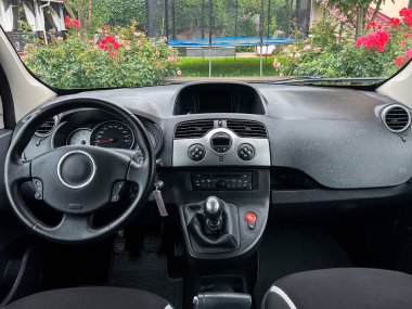 Güzel dizayn edilmiş bir arabanın içinde modern bir gösterge paneli, sezgisel kontroller, rahat koltuklar ve renkli çiçeklerden oluşan bir zemin vardır.