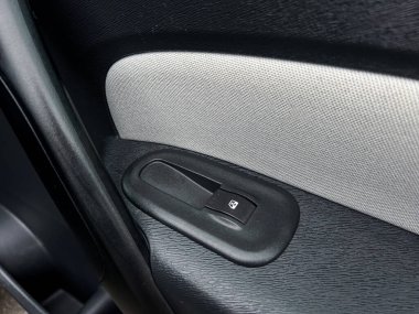 Bu detaylı yakın çekim görüntüsü, işlevselliğiyle birlikte modern şık tasarımını gösteren bir araç kapı panelinde bulunan güç penceresi kontrol anahtarını yakalar.