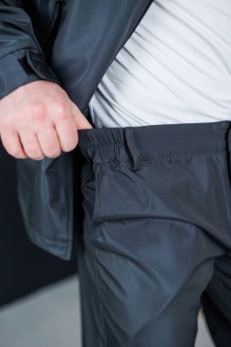 Gösterişli siyah eşofmanlı şık bir adam cebini modern bir iç mekâna yerleştirir. Etkin yaşam tarzları için şık ama şık kıyafetler giyer.