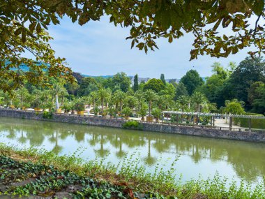 Bereketli ağaçlar ve sakin sularla dolu güzel bir nehir kenarı parkı keşfedin. Rahatlamak ve eğlenmek için ideal bir yer.