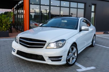 Çarpıcı beyaz bir lüks sedan canlı bir şehirde park edilmiş zarif tasarımı ve etkileyici özellikleriyle araba meraklılarına ve sıradan hayranlarına çekici geliyor.