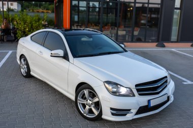 Kentsel bir ortamda şık beyaz bir coupe modern tasarımı ve şık çizgileri ile park edilir. Otomotiv tutkunları ve tüm araba severler için mükemmel.