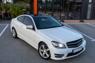 Dinamik bir şehirde, gösterişli beyaz bir MercedesBenz coupe seçkin tasarımı, gelişmiş teknolojisi ve otomotiv karmaşıklığını tanımlayan lüksünü gözler önüne seriyor.