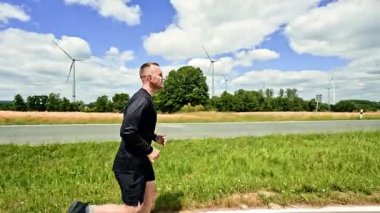 Atletik güçlü sağlıklı koşucu. Genç bir adam güneşli bir günde sabah koşusunda. Açık havada kardiyo eğitimi. Sağlıklı bir yaşam tarzı. Siyah şortlu ve formalı adam..