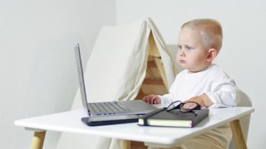 Gözlüklü çocuk bilgisayardaki masada oturuyor. Çocuk işadamı evde dizüstü bilgisayarla çalışıyor. Yeni yürümeye başlayan çocuk girişimciyi oynuyor. Ofiste bilgisayarla oynayan bir çocuğun portresi..