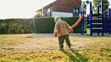 Parktaki oyun parkında çimlerde oynayan bir çocuk. Yeni yürümeye başlayan çocuk çevreyi keşfediyor. Yazın çocuk dışarıda yürüyor..