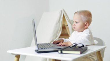 Gözlüklü çocuk bilgisayardaki masada oturuyor. Çocuk işadamı evde dizüstü bilgisayarla çalışıyor. Yeni yürümeye başlayan çocuk girişimciyi oynuyor. Ofiste bilgisayarla oynayan bir çocuğun portresi..