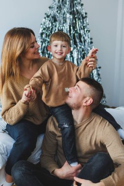 Neşeli bir aile, bu büyüleyici bayram döneminde, birbirine uyumlu süveterlerle, sevgi, sıcaklık ve birlikteliği kutlayan sevimli bir Noel ağacının etrafında toplanır.
