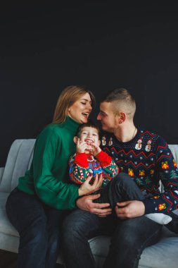 Yürek ısıtan bir aile portresi, sevgi dolu aileleri ve onların sevimli çocuklarını renkli Noel süveterleri içinde gösteriyor. Bu şenlik sezonunda sevgilerini ve birlikteliklerini vurguluyorlar.