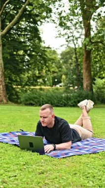 Sevimli çocuk ve baba birlikte vakit geçiriyorlar. Küçük çocuk ve babası çimlerin üzerinde otururken dizüstü bilgisayara bakıyorlar. Baba ve oğul parkta vakit geçiriyorlar. Mutlu babalık ve eğlenceli çocukluk.