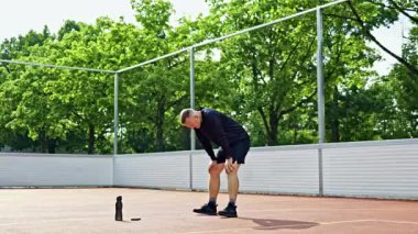 Şortlu ve tişörtlü yakışıklı bir adam parkta spor salonunda antrenman yapıyor. Bir adam dışarıda antrenman yapıyor. Bir spor yaşam tarzı.