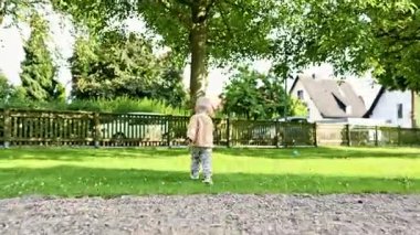 Parkta yeşil çimlerde koşan neşeli 2 yaşında bir çocuk. Çocuk parkta oyun oynuyordu. Neşeli çocuk dışarıda çimenlerde koşuyor. Çocuk gelişimi.