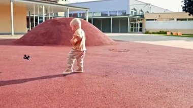 Şehir parkında çocuk parkında koşan neşeli çocuk. Çocuk sokakta oyun parkında oynuyor. Çocuk dışarıda yürüyor. 2 yaşında şık giyinmiş bir çocuk..