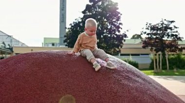 Şehir parkında çocuk parkında koşan neşeli çocuk. Çocuk sokakta oyun parkında oynuyor. Çocuk dışarıda yürüyor. 2 yaşında şık giyinmiş bir çocuk..