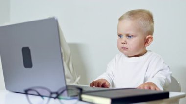 Gözlüklü yakışıklı işadamı masada oturmuş dizüstü bilgisayara bakıyor. Küçük çocuk oturmuş bilgisayarda çizgi film seyrediyor. Taşınabilir bir bilgisayarda video izleyen çocuk.