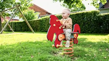 Oyun parkında salıncakta oturan gülümseyen çocuk. Çocuk dışarıda oynuyor. Salıncakta sallanan bir çocuk. Oyun parkındaki çocuklar için eğlence eğlenceleri.